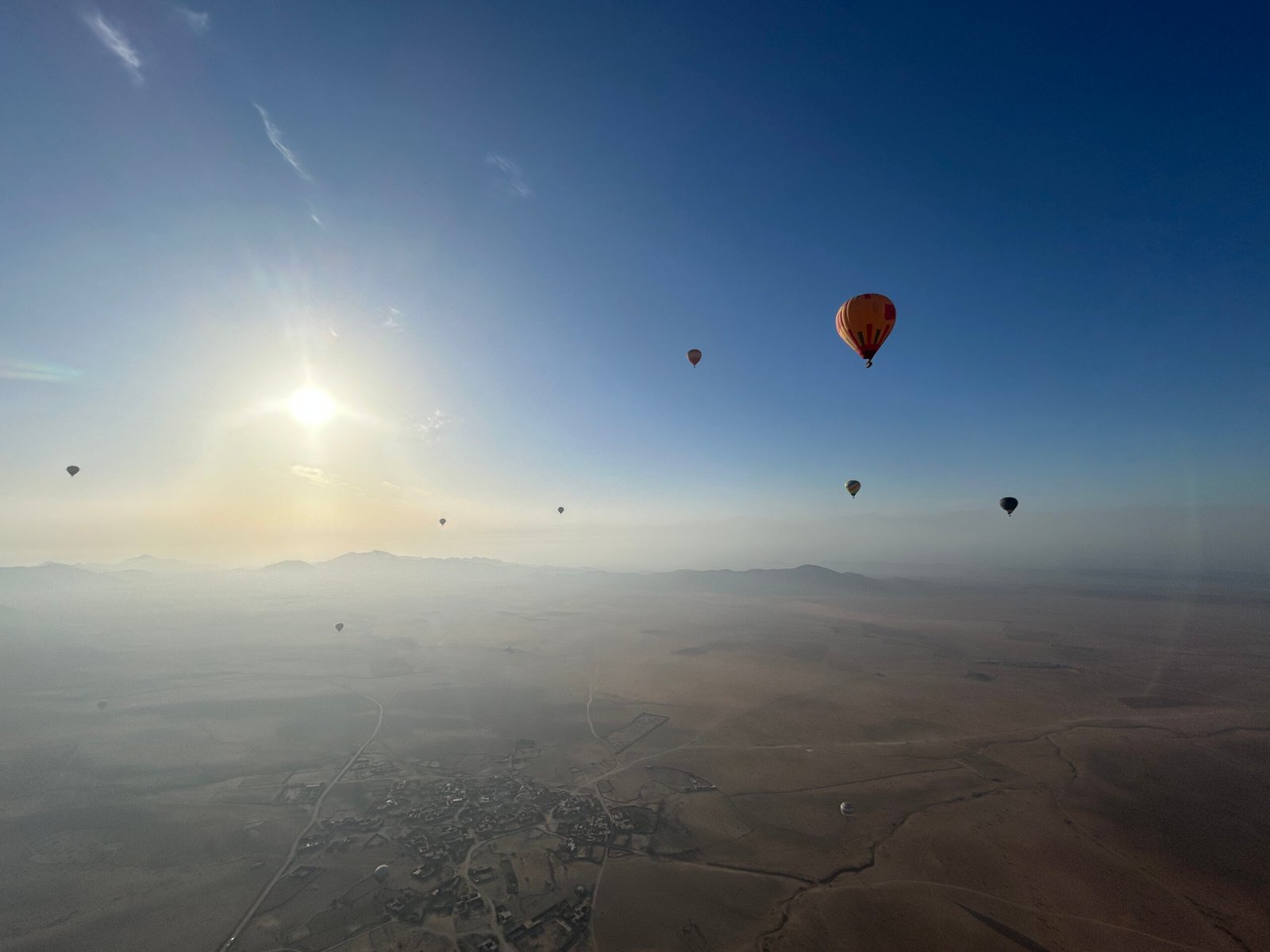 Plusieurs montgolfière colorés vue du ciel au dessus du désert d'Agafay.