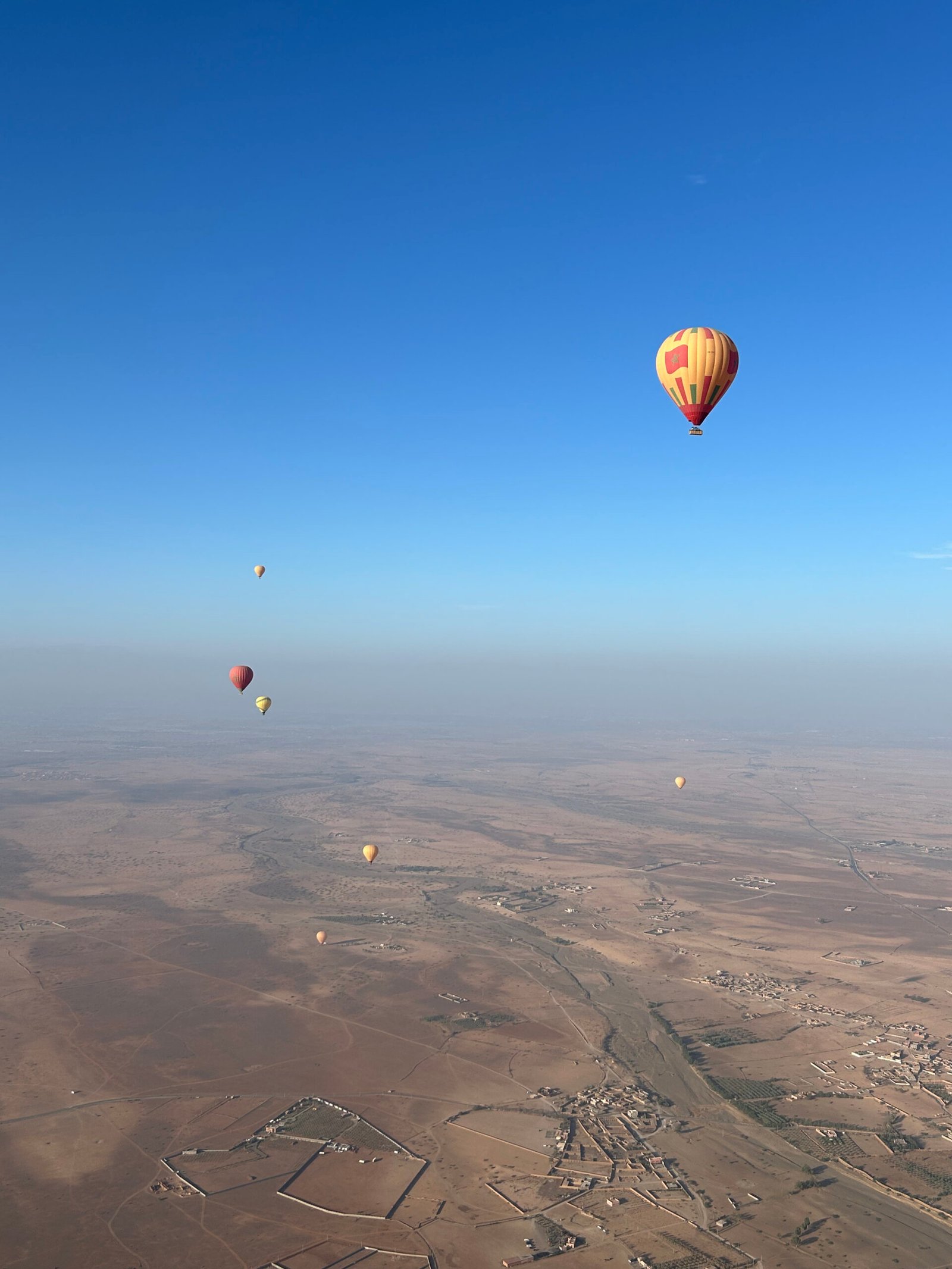 Vue sur le désert d'Agafay avec deux montgolfière dans les airs.