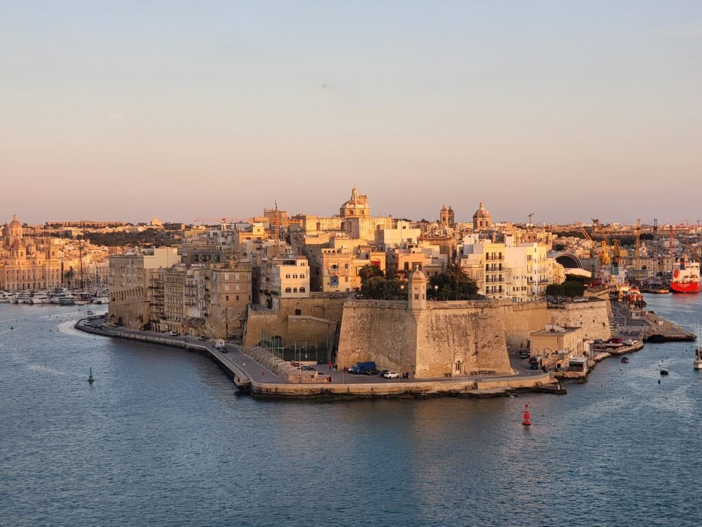 Scenic aerial view of Valletta, Malta, during sunset showcasing its historic architecture along the coastline.